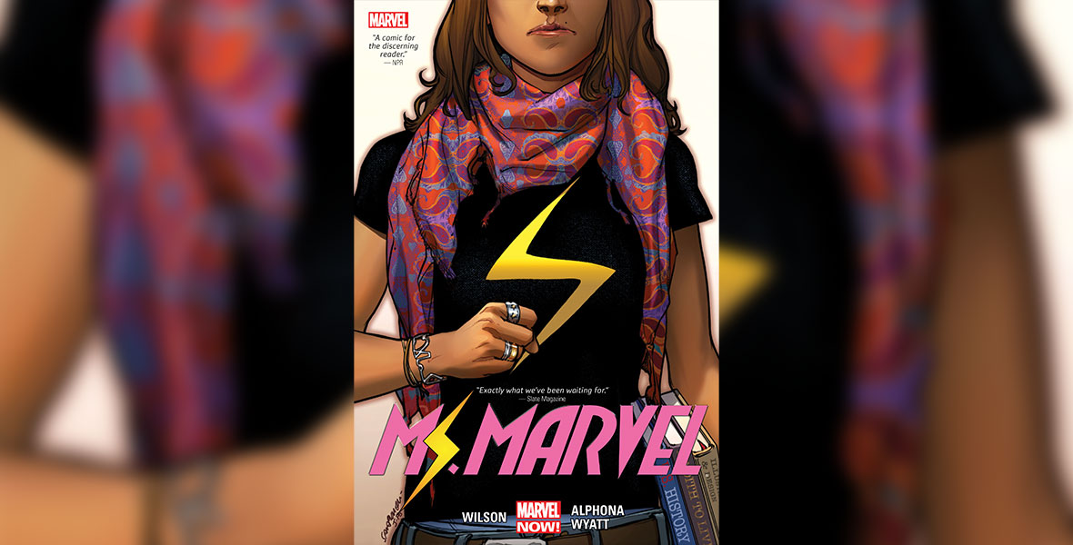 Cover image from the first issue of Ms. Marvel (2014-2015) shows the teenage Ms. Marvel from mid-face to waist. She holds several schoolbooks in her right hand, while making a fist with her left hand. Her black T-shirt is emblazoned with a yellow lightning bolt.