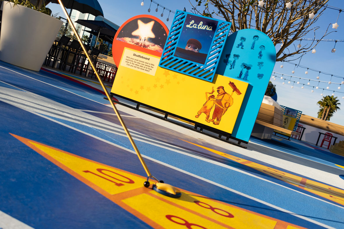 The shuffleboard court at Pixar Place Hotel is themed after the Pixar short La Luna, and seen here in close up are the end of a shuffle stick and a disk in with a yellow star on top, sitting aboard the scoring triangle at one end of the court.