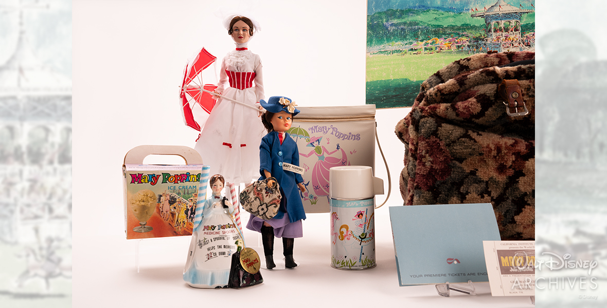 Depicted are various Mary Poppins merchandise items, including two Mary Poppins dolls. One doll is tall and dressed in white, with a red-and-white umbrella, while the other, smaller doll is holding a carpet bag and wearing a blue coat and matching blue hat with flowers. There is also a cardboard ice cream box that reads “Mary Poppins Ice Cream” and features characters from the film riding carousel horses. A ceramic Mary Poppins figurine with two ceramic measuring spoons is featured, along with a lunch bag featuring an illustration of Mary Poppins in a pink-colored dress, with matching thermos featuring the film’s characters riding carousel horses.
